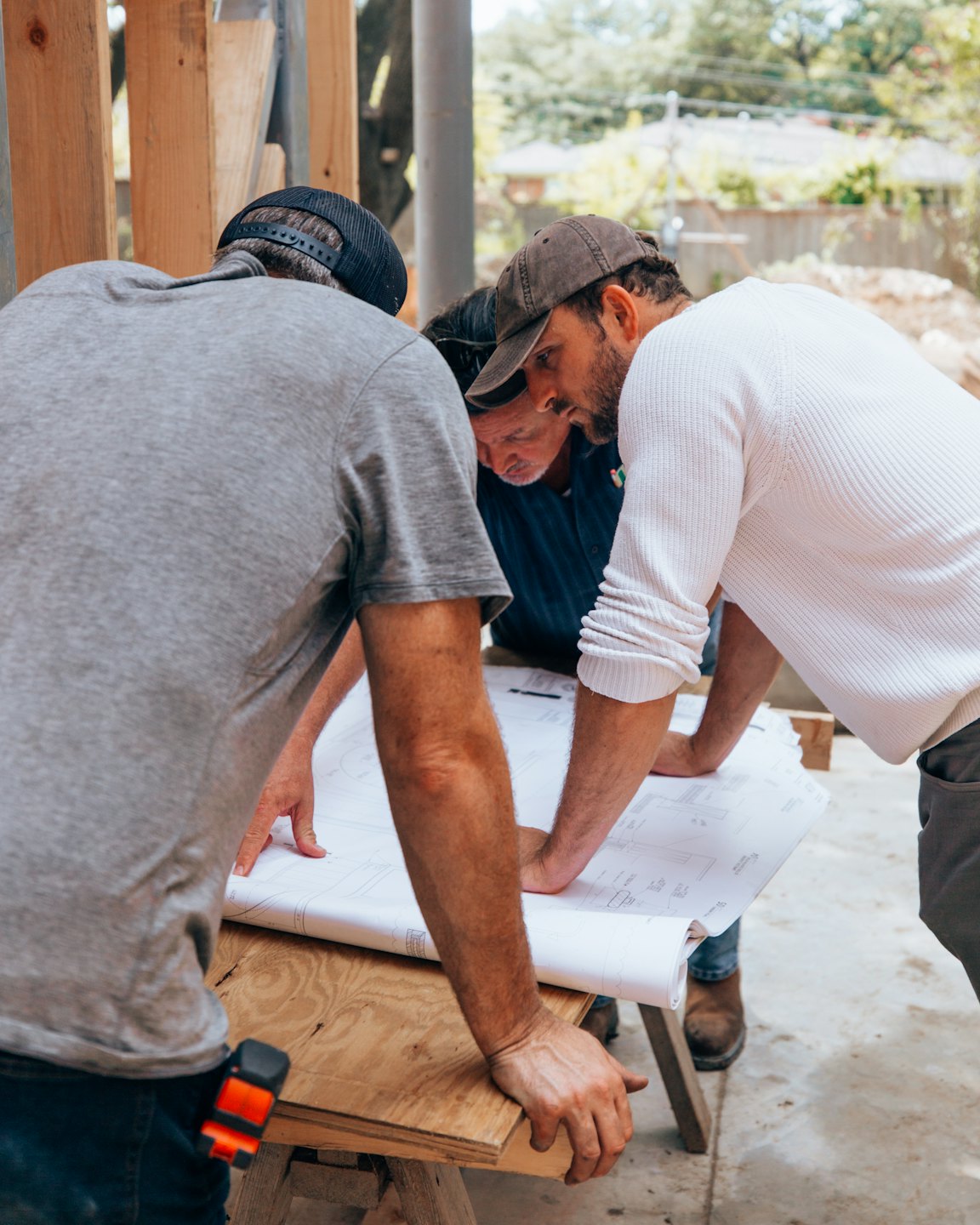 Bauarbeiter besprechen Baupläne auf einer Baustelle im Freien.