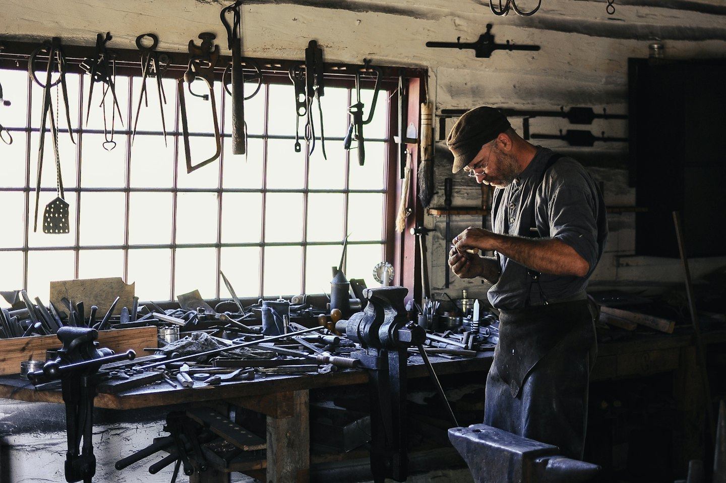 Handwerker arbeitet sorgfältig an einem kleinen Objekt an seiner Werkbank.